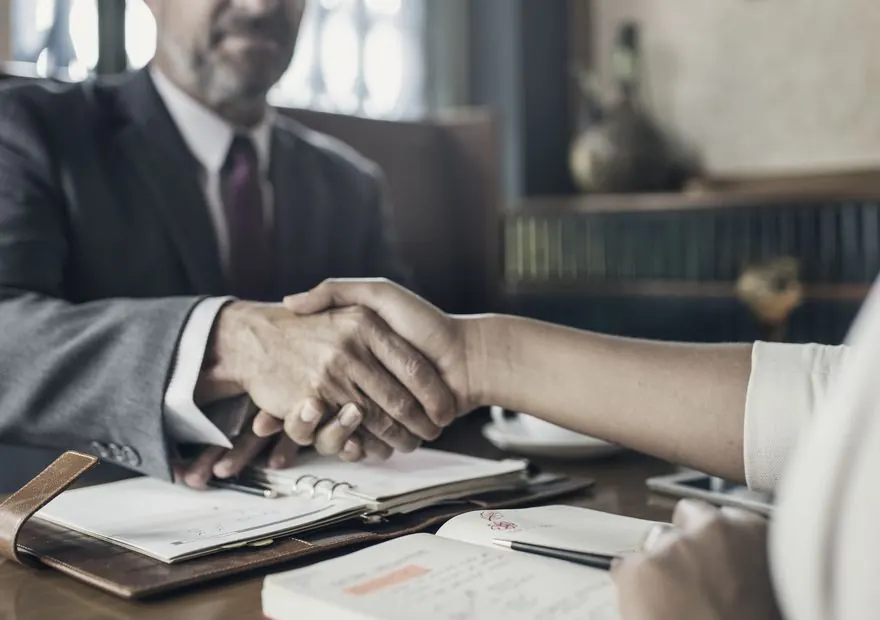 Attorney and client shaking hands across a desk